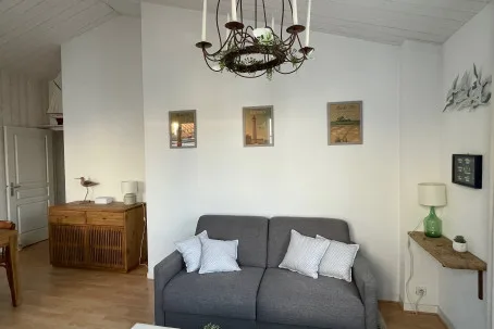 Una sala de estar con asientos grises bajo una lámpara colgante decorativa.