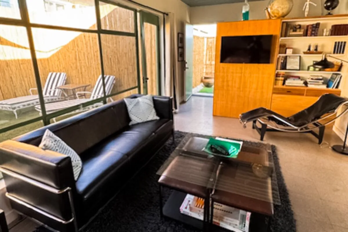 A living room with dark seating, a coffee table, and a wall-mounted television.