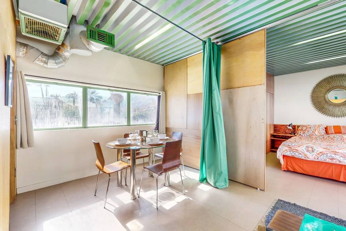 A dining area with a table and chairs beside a curtained sleeping area.