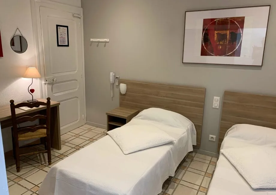Representative hotel space: A twin bedroom with two beds, a desk, and framed artwork.