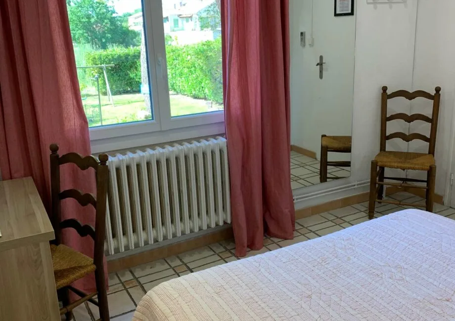 Representative hotel space: A bedroom with a bed, chairs, and a window overlooking greenery.