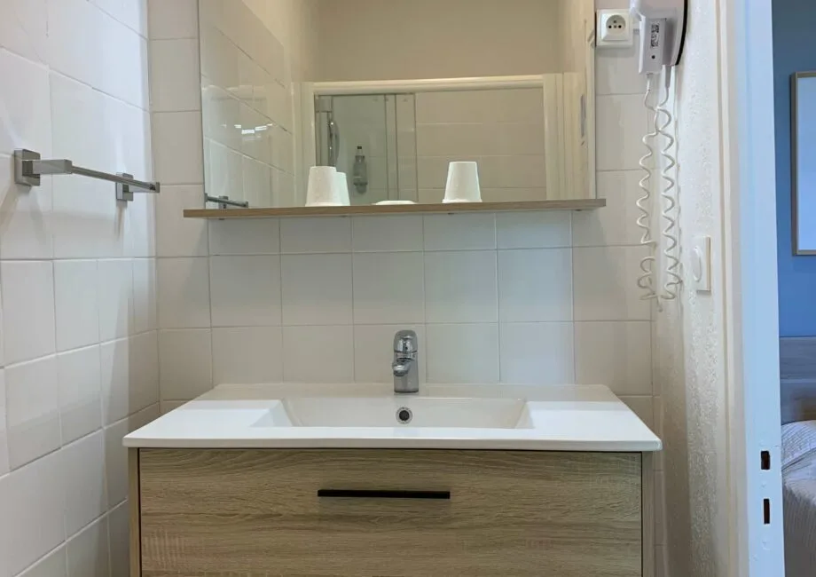 Representative hotel space: A tiled bathroom vanity with a wide mirror above the sink.