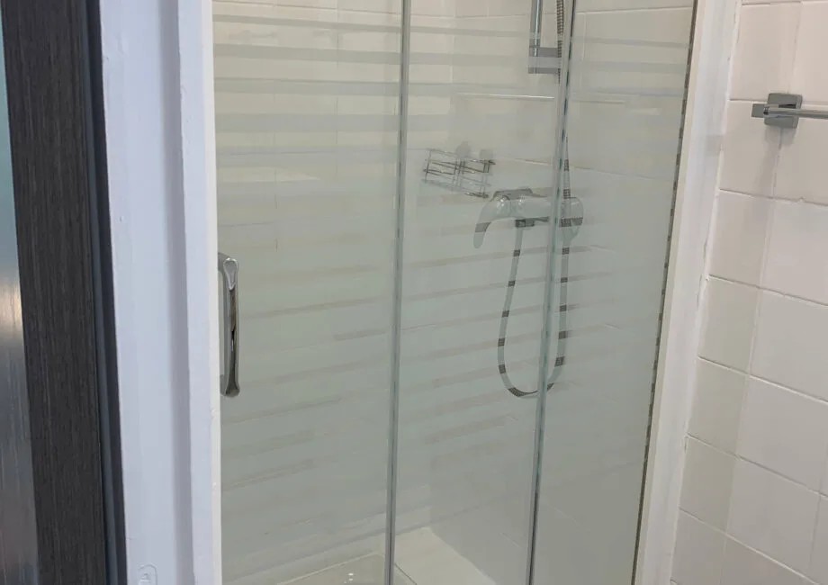 Representative hotel space: A tiled bathroom with a glass shower and wall-mounted fixtures.