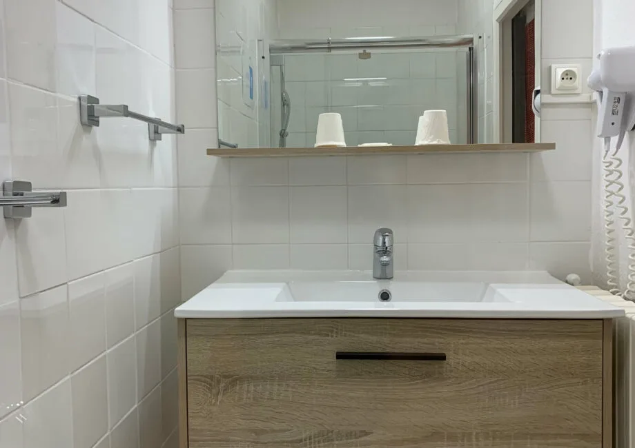 Representative hotel space: A tiled bathroom with a sink and a wide mirror above the vanity.