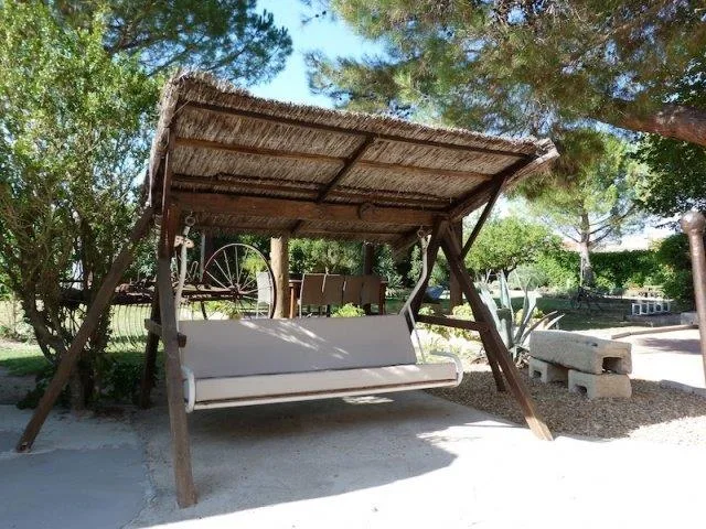 Representative hotel space: A shaded outdoor seating area features a wooden swing beneath a thatched canopy.