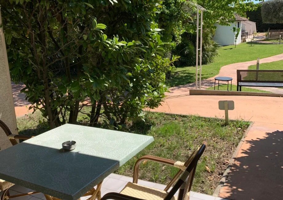 Representative hotel space: Outdoor patio seating beside a garden path and green lawn.