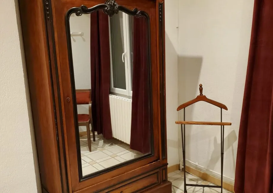 Representative hotel space: A bedroom wardrobe with a mirror stands beside a clothes rack.