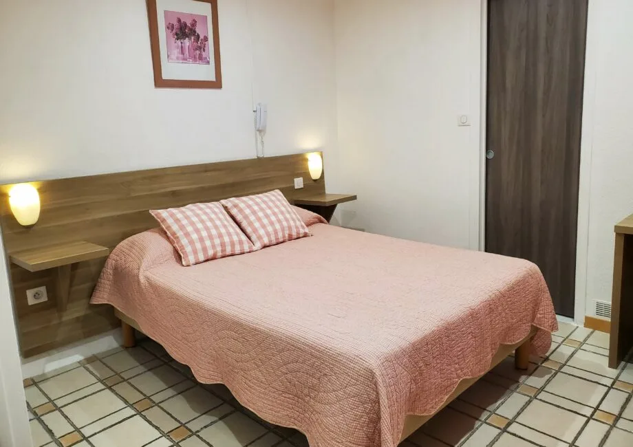 Representative hotel space: A bedroom with a double bed, pink bedding, and bedside shelves.