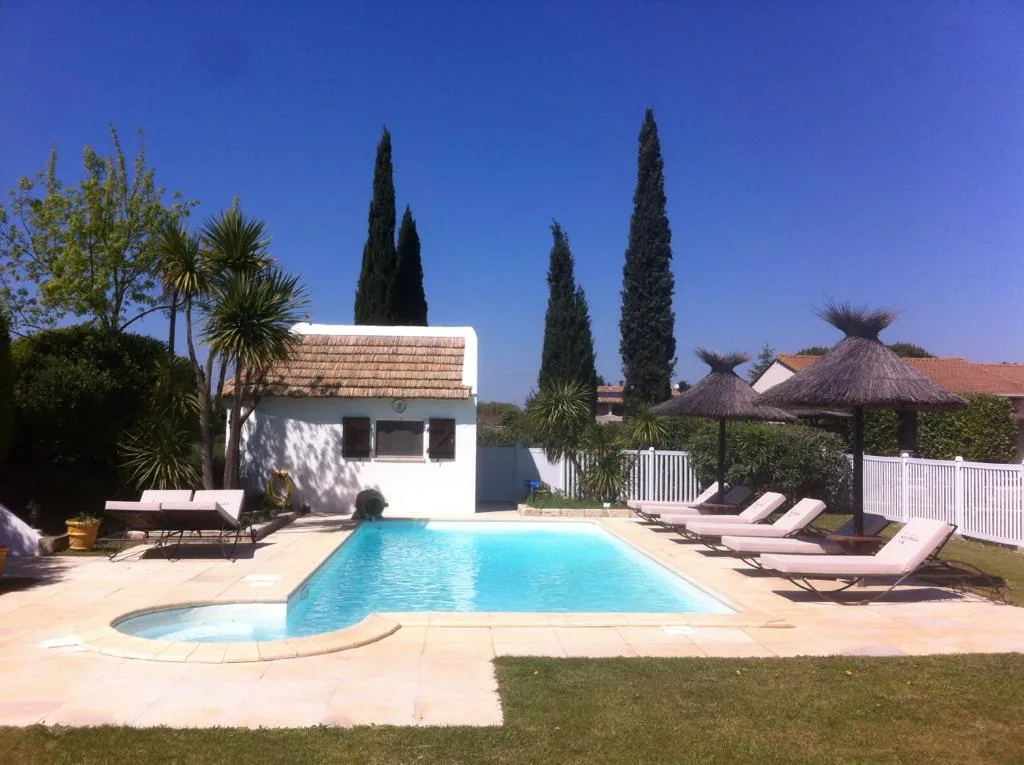 Representative hotel space: An outdoor swimming pool is surrounded by lounge chairs and thatched parasols.