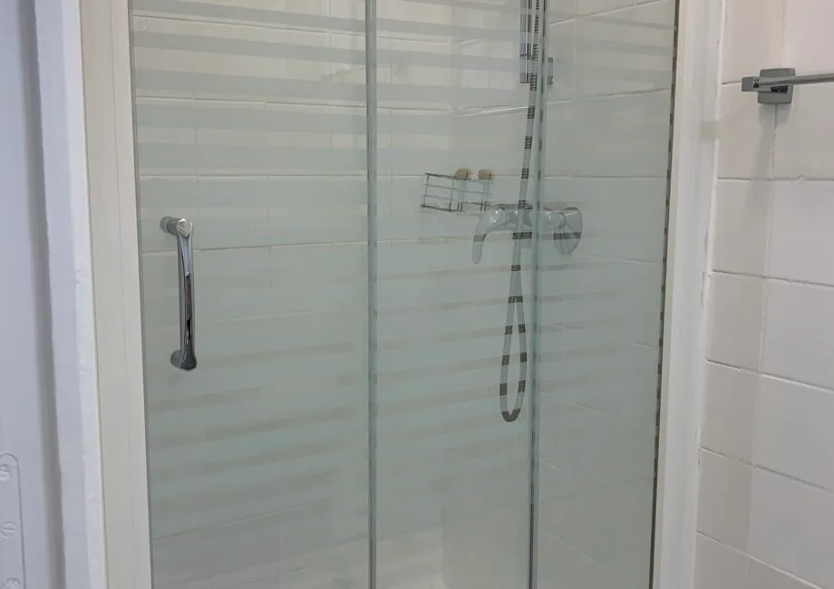 Representative hotel space: A tiled bathroom with a glass shower and wall-mounted fixtures.
