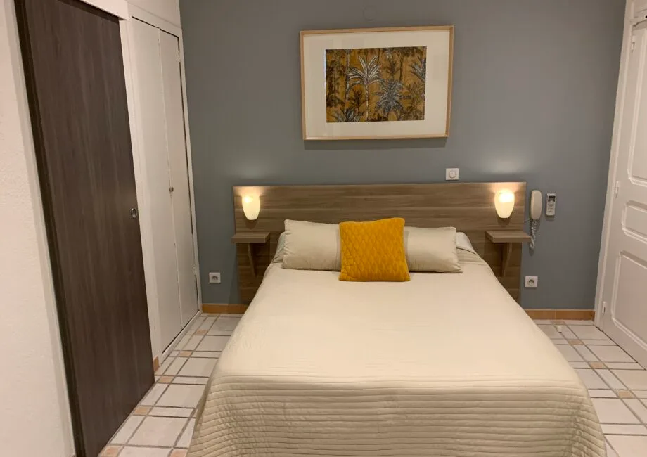 Representative hotel space: A bedroom with a neatly made bed and framed artwork above the headboard.