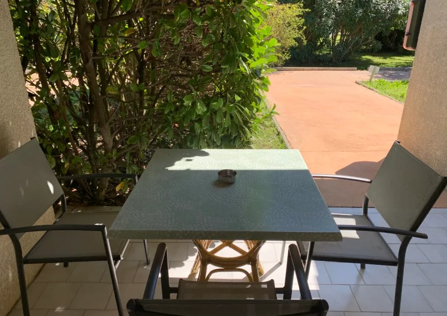 Representative hotel space: An outdoor patio table with seating overlooks a paved walkway and leafy shrubs.