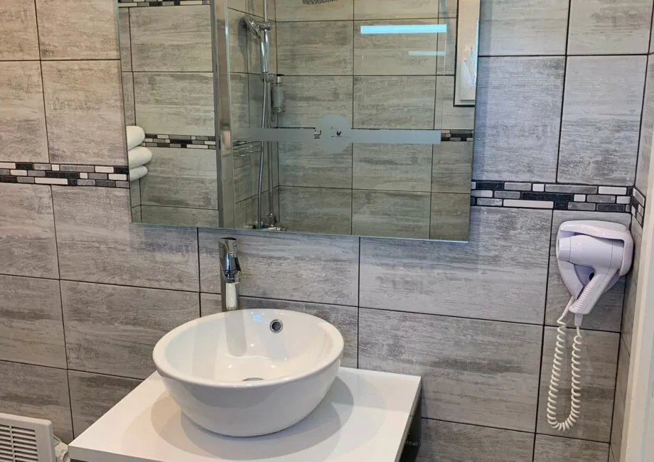 Representative hotel space: A tiled bathroom with a round basin beneath a wall mirror.