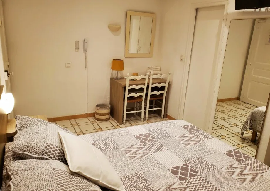 Representative hotel space: A bedroom with patterned bedding and a small desk with chairs.