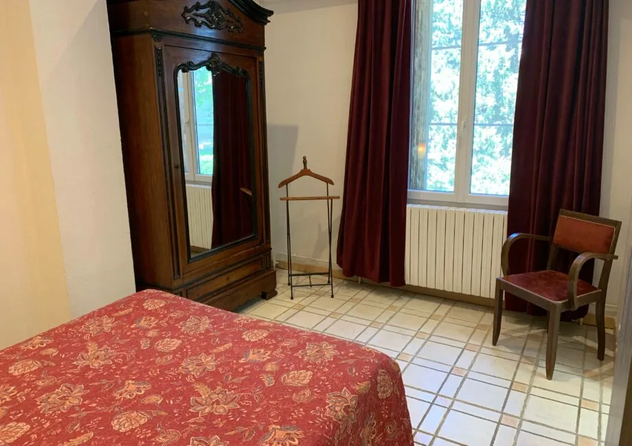 Representative hotel space: A bedroom with a patterned bedspread, wardrobe, and window with dark curtains.