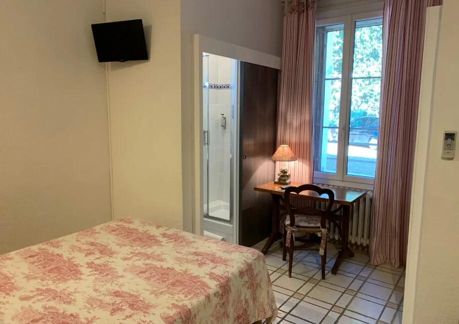 Representative hotel space: A bedroom with a floral bedspread and a small desk beside the window.