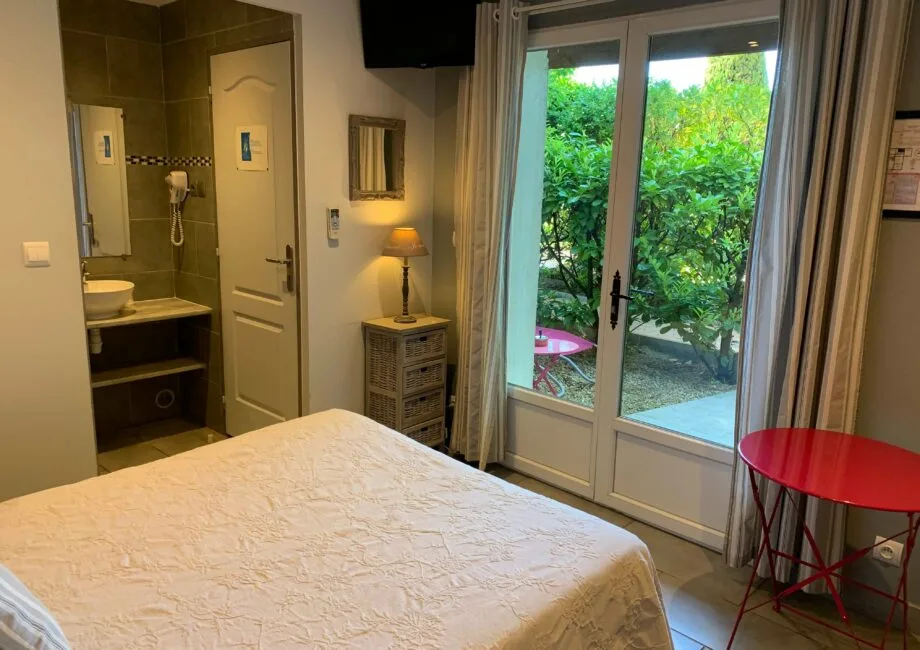 Representative hotel space: A bedroom with a bed beside glass doors opening onto greenery.