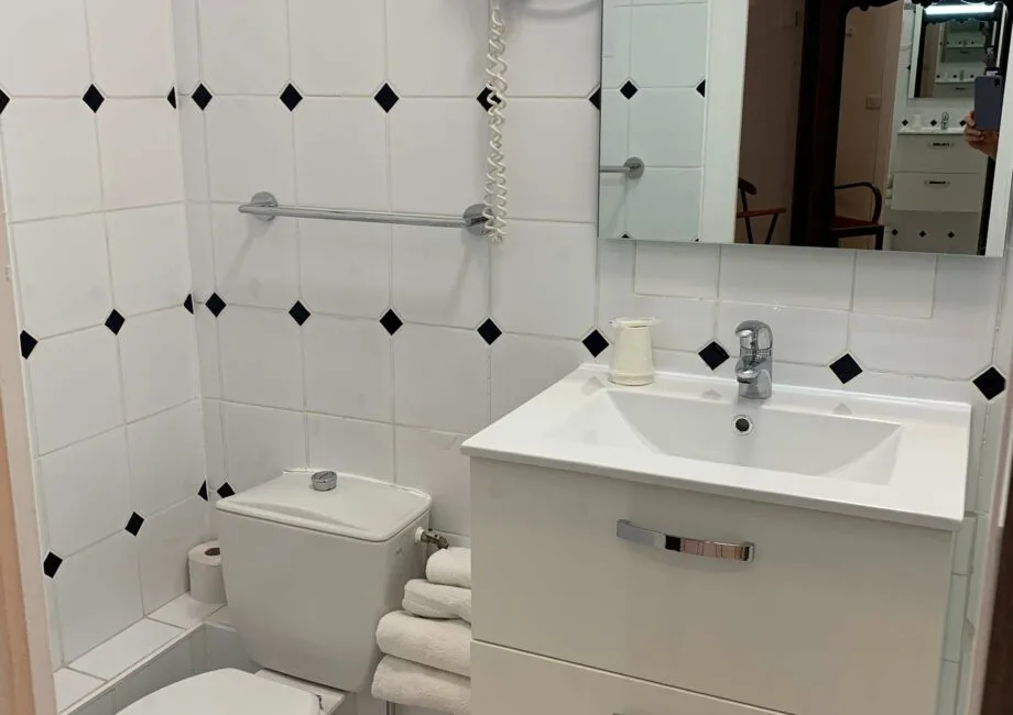 Representative hotel space: A tiled bathroom with a sink, mirror, and toilet.