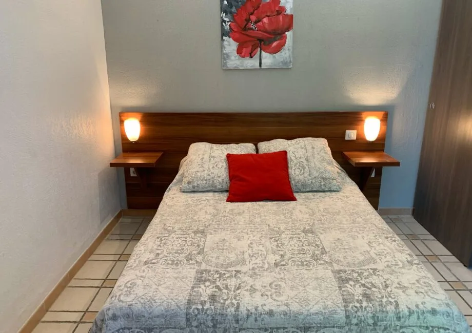 Representative hotel space: A bedroom with a double bed, patterned bedding, and a red accent pillow.