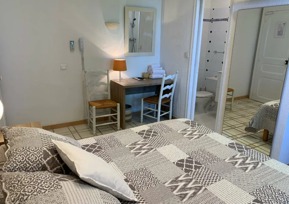 Representative hotel space: A bedroom with a patterned bedspread and a desk beside the bed.