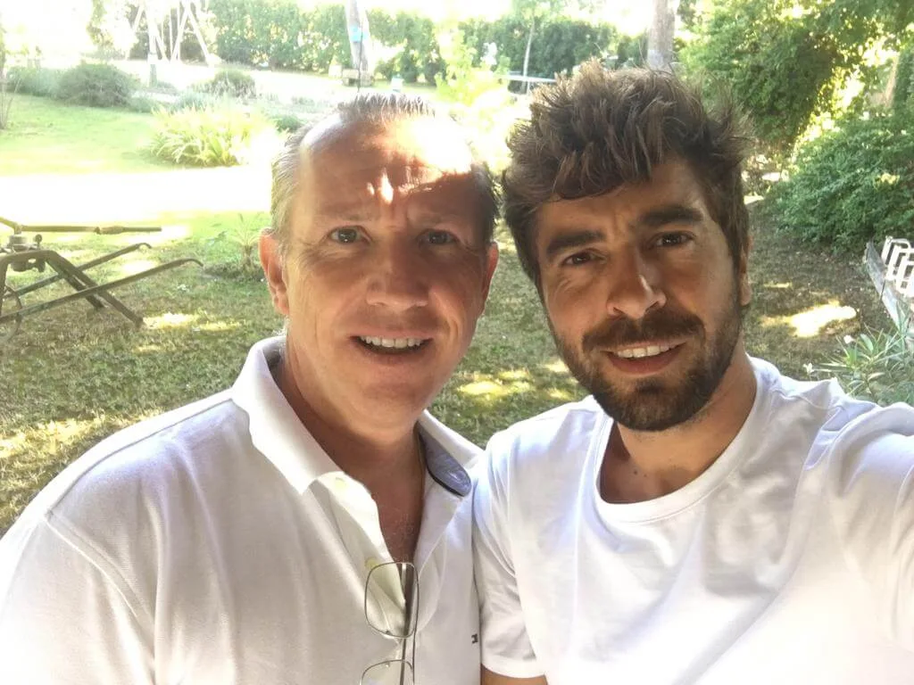 Representative hotel space: Two men pose for a selfie outdoors in a sunny garden.