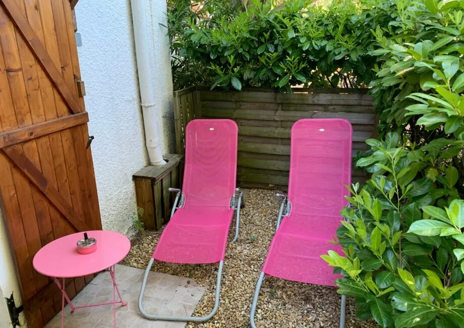 Representative hotel space: A small outdoor patio with pink lounge chairs and leafy shrubs.