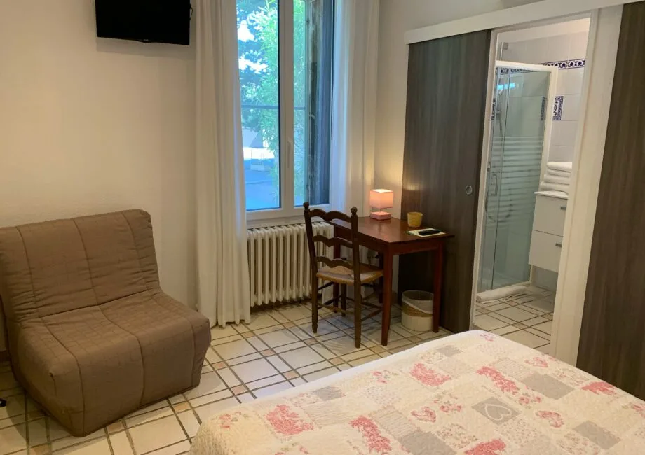 Representative hotel space: A bedroom with a desk beside the window and a bathroom doorway.
