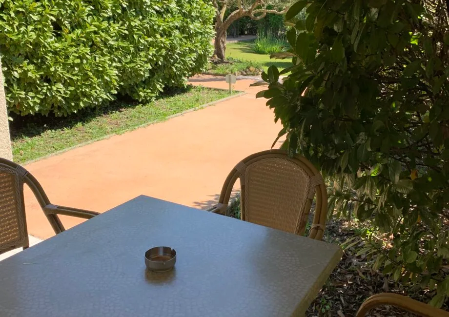 Representative hotel space: Outdoor patio seating beside a garden path and leafy hedges.