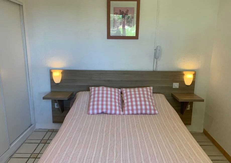 Representative hotel space: A bedroom with a bed, checkered pillows, and wall-mounted bedside lights.