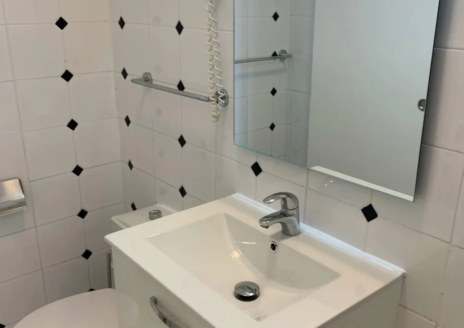 Representative hotel space: A tiled bathroom with a white sink and wall mirror.