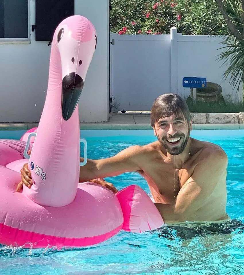 Representative hotel space: A man poses in a swimming pool beside a large pink flamingo float.