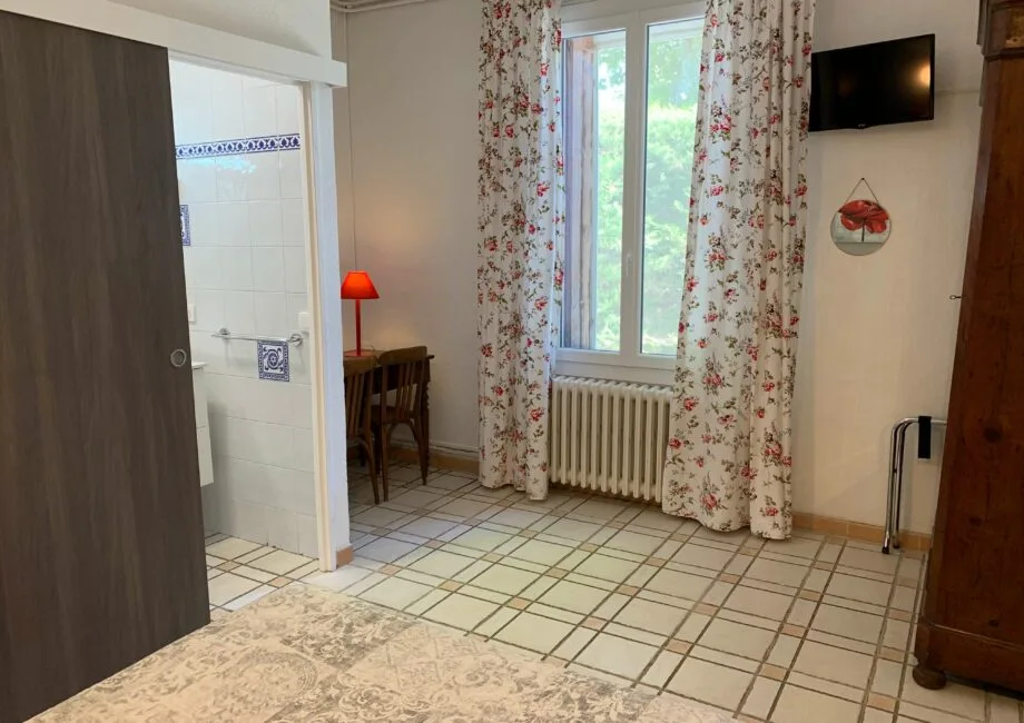 Representative hotel space: A tiled room with a window, floral curtains, and a small table.