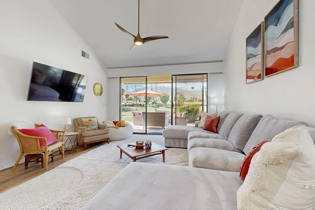 A bright living room has seating around a coffee table and sliding glass doors.