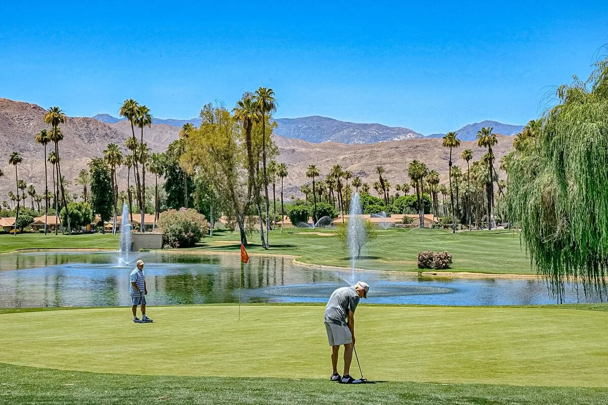 Shared amenity: A golf course with golfers playing beside a pond and fountains.