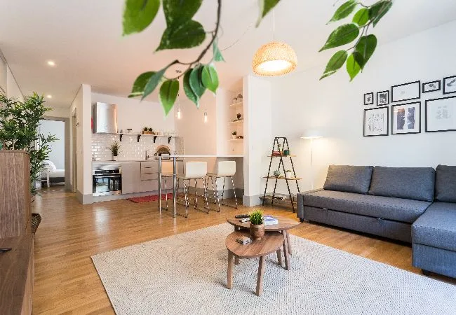 Una luminosa sala de estar con asientos junto a una cocina y comedor abiertos.