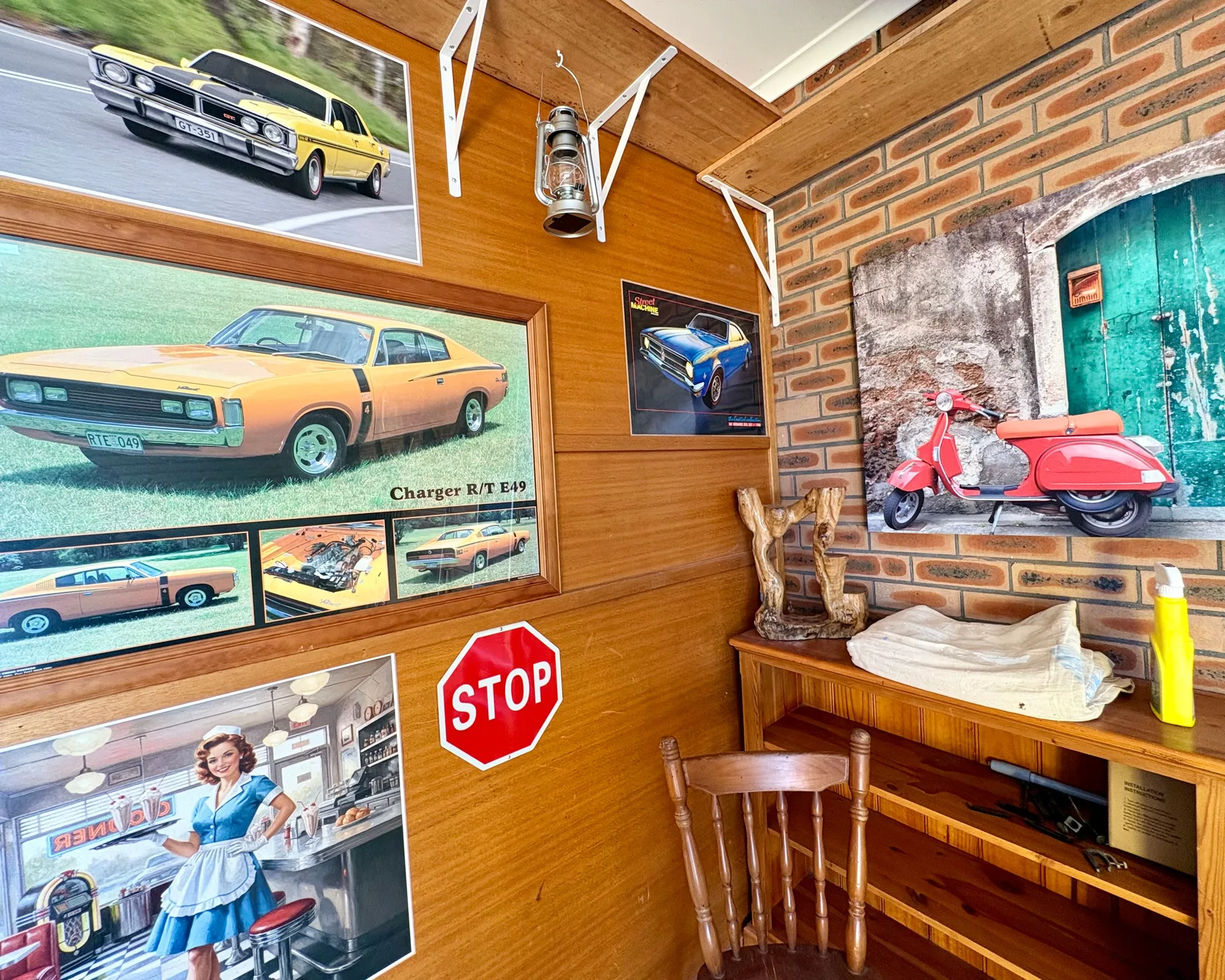 Un espacio decorado con madera presenta carteles de autos clásicos y una moto roja.