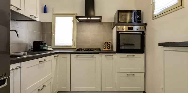 Una cocina luminosa con gabinetes blancos, encimera y electrodomésticos de cocina integrados.