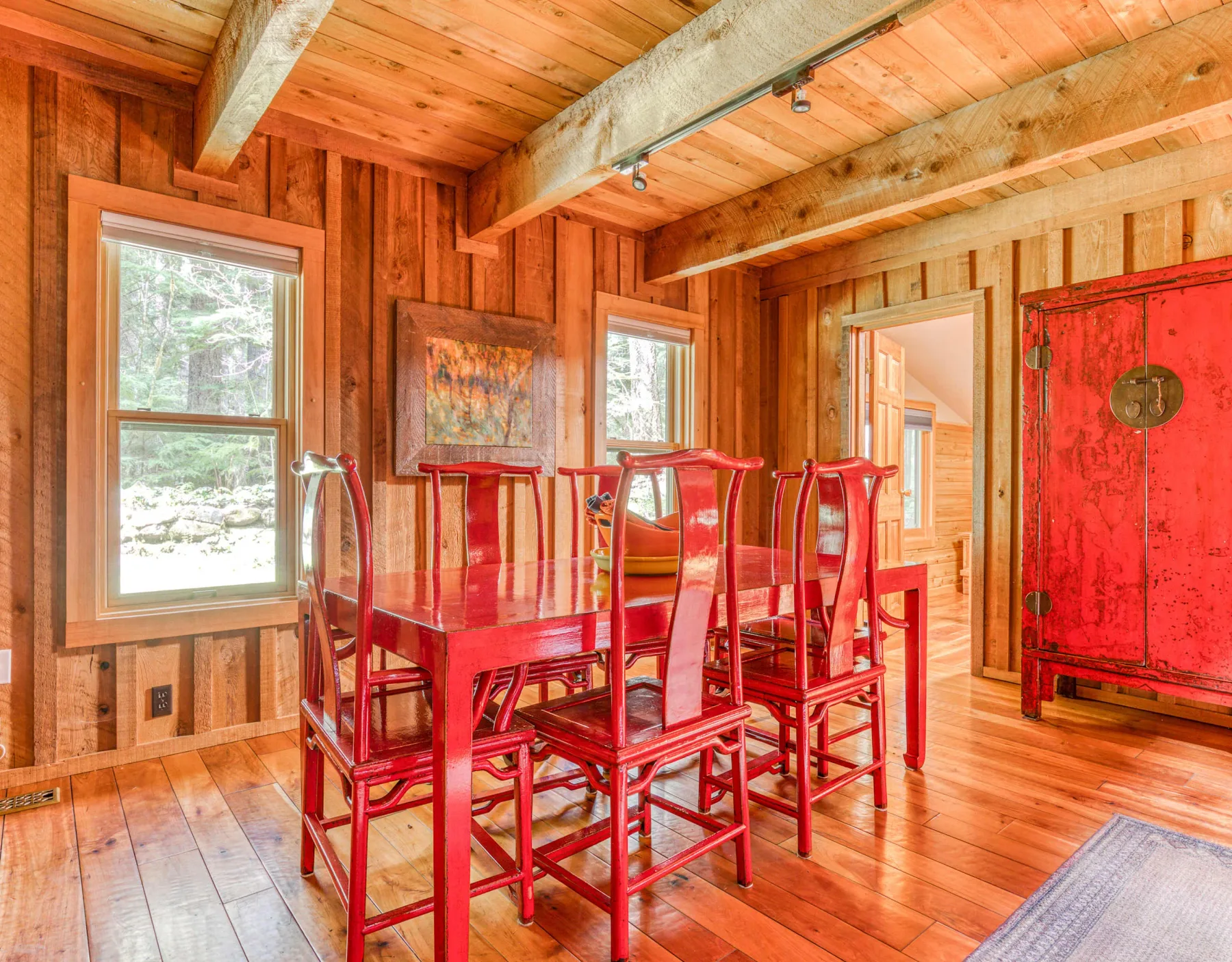 Comedor revestido de madera con asientos rojos y un gran armario rojo.