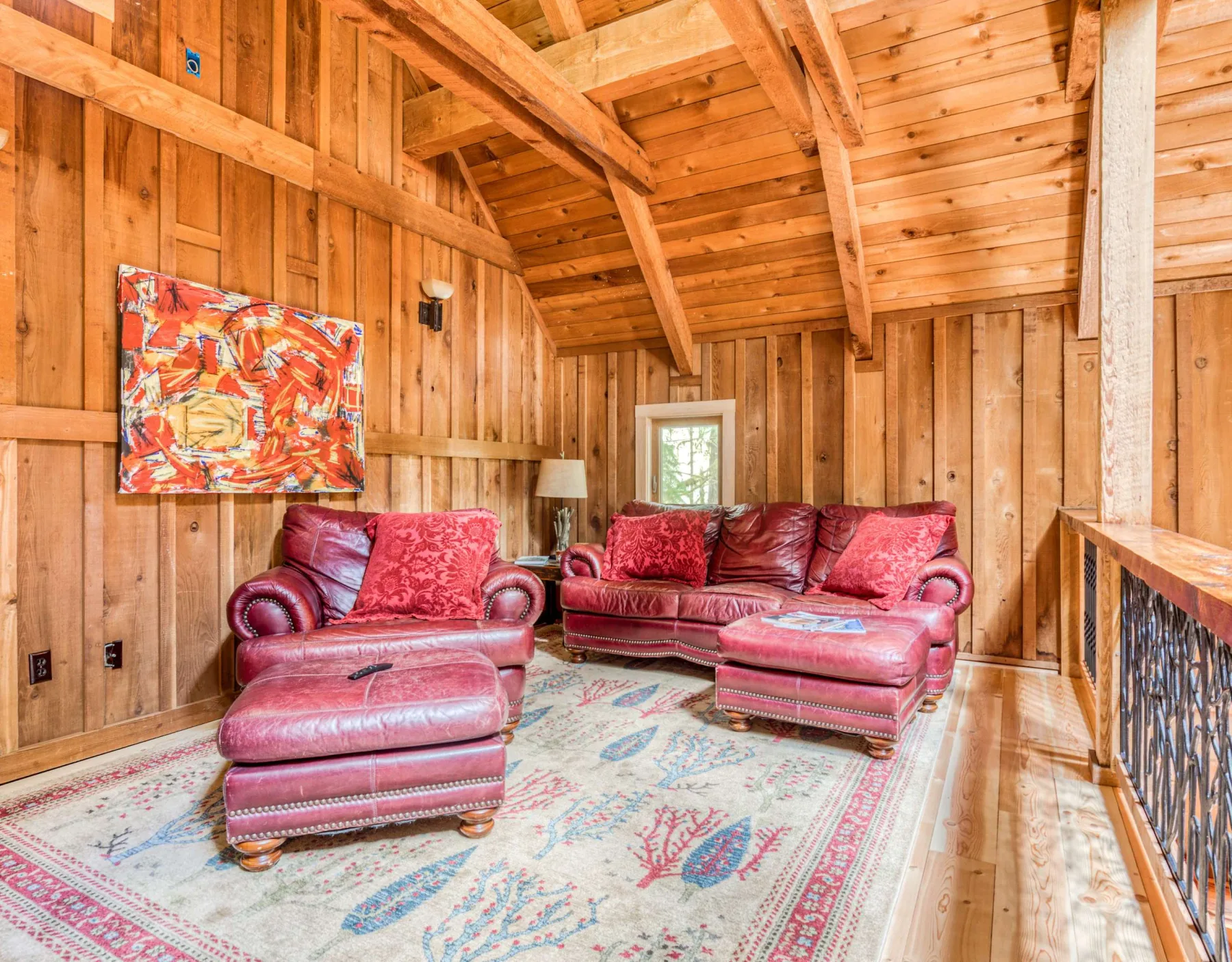 Sala revestida de madera con asientos rojos y una alfombra estampada.