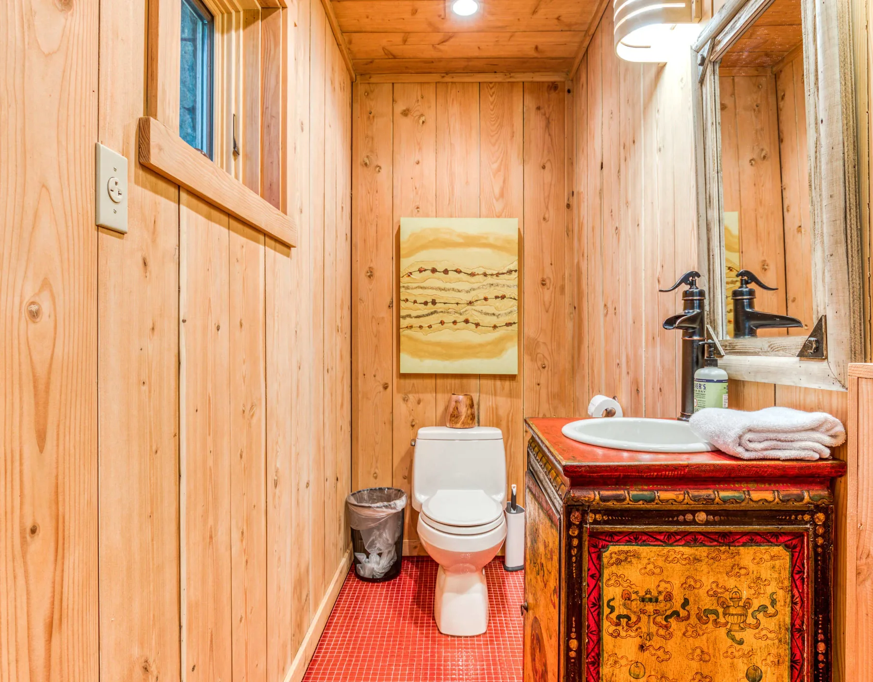 Un baño revestido de madera con un inodoro y un lavabo.