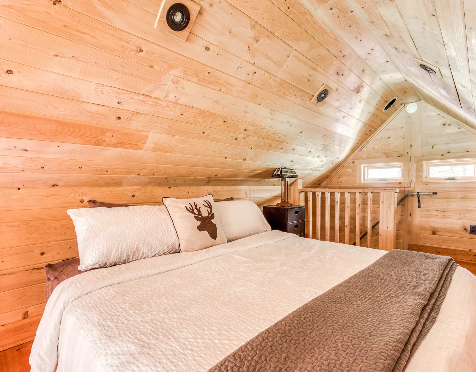 Un dormitorio con una cama bajo un techo inclinado revestido de madera.