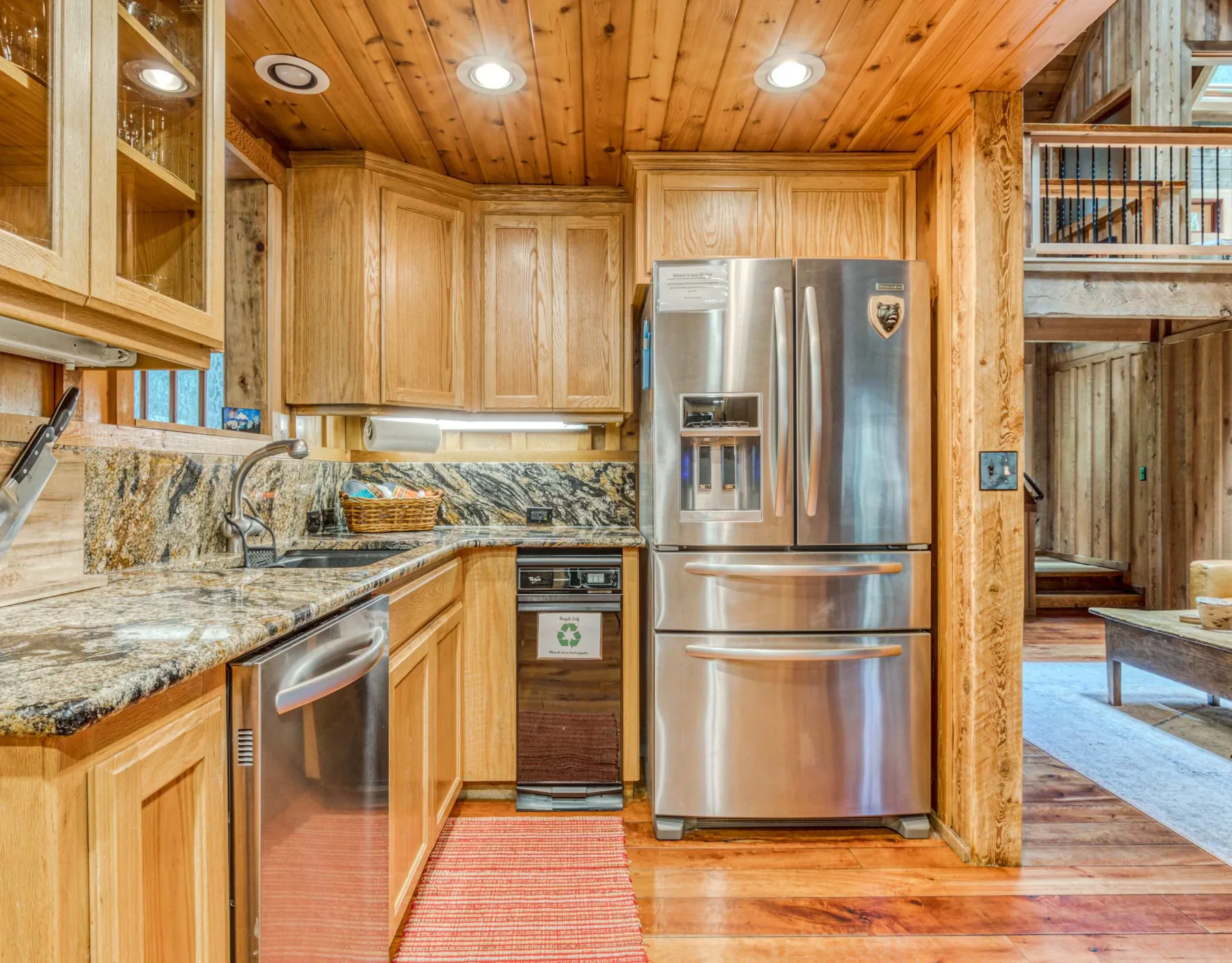 Una cocina revestida de madera con encimera de piedra y refrigerador de acero inoxidable.