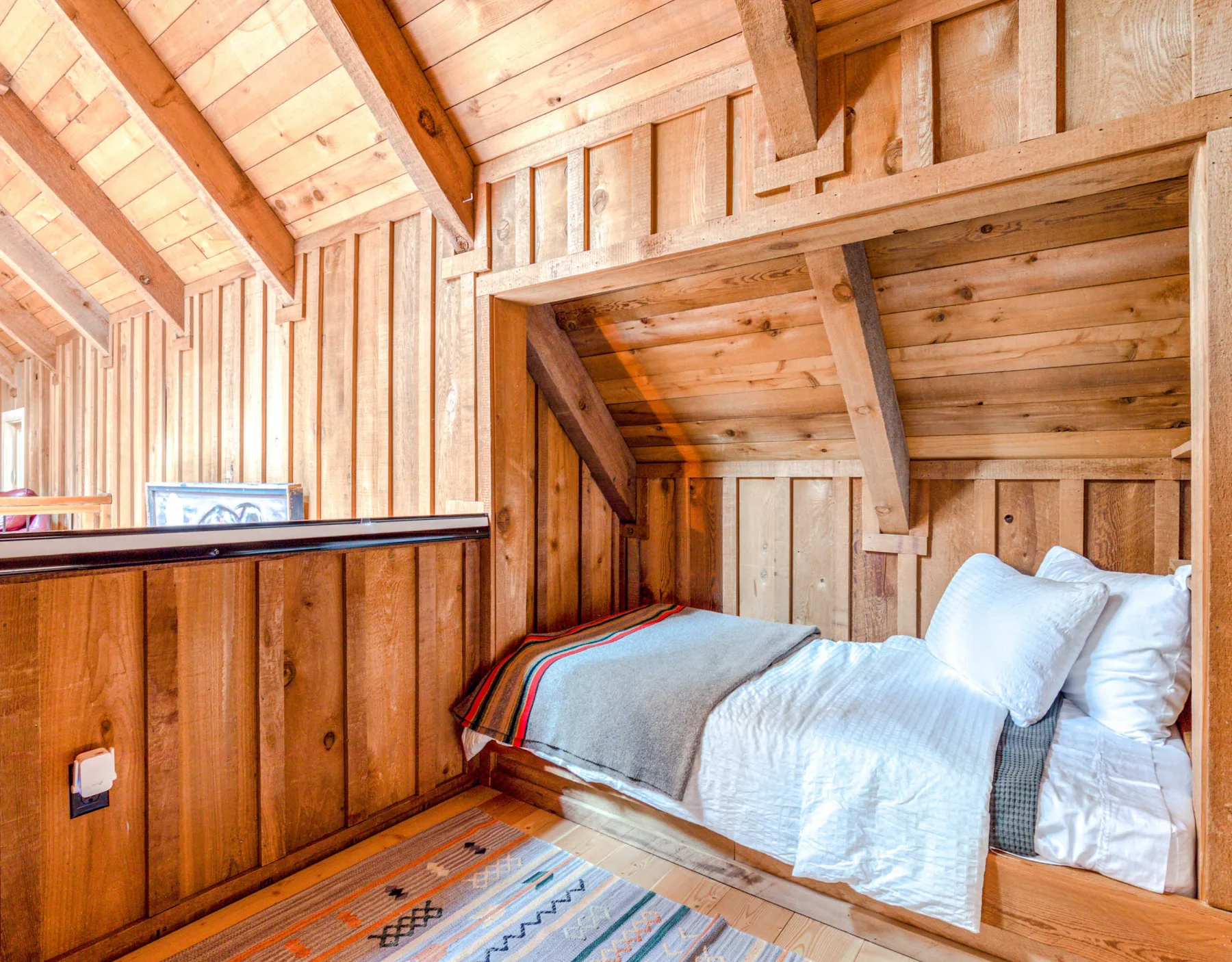 Un dormitorio revestido de madera con una cama bajo un techo inclinado.