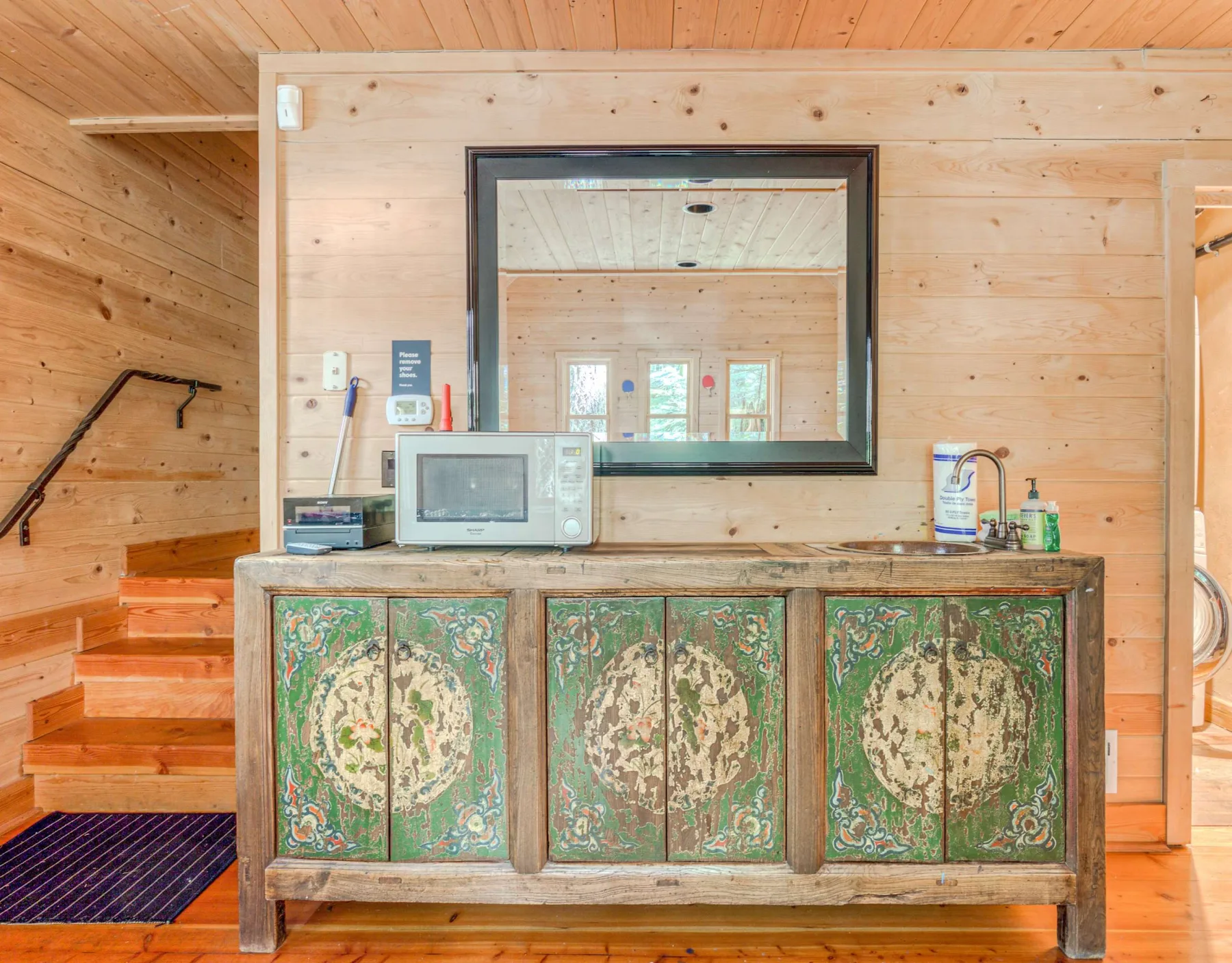 Interior de madera con un armario pintado, un microondas y un espejo grande.
