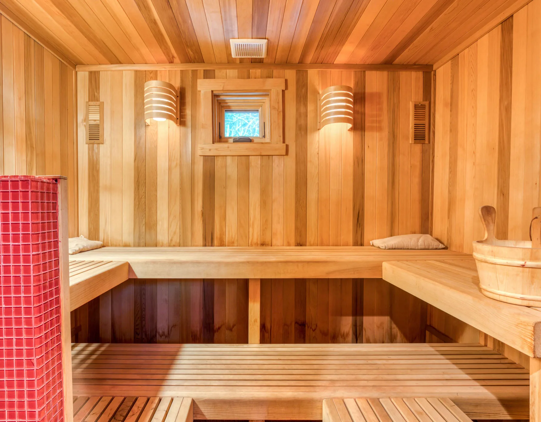 Una sauna revestida de madera, con asientos escalonados e iluminación cálida en las paredes.
