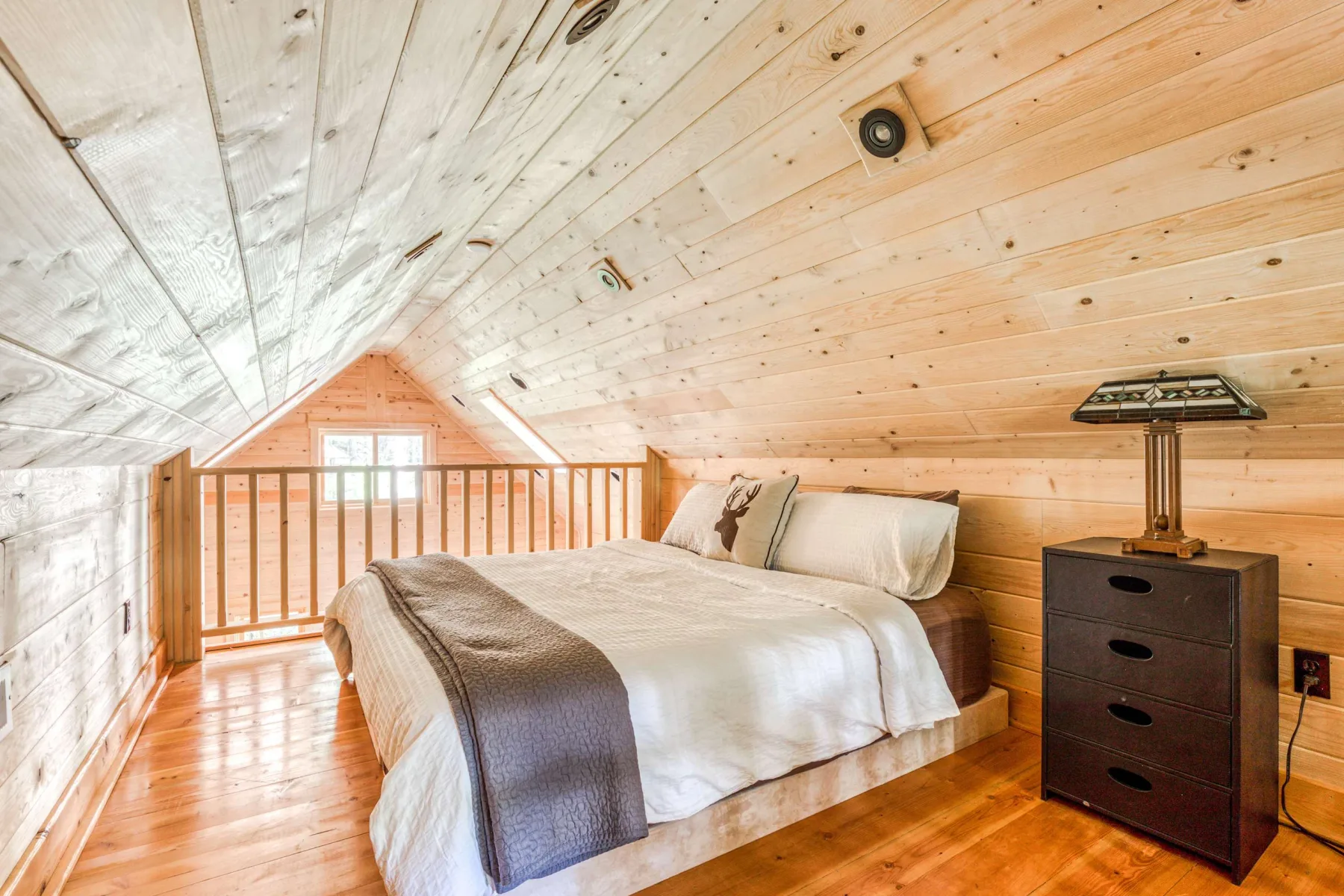 Un dormitorio con una cama bajo un techo inclinado revestido de madera.