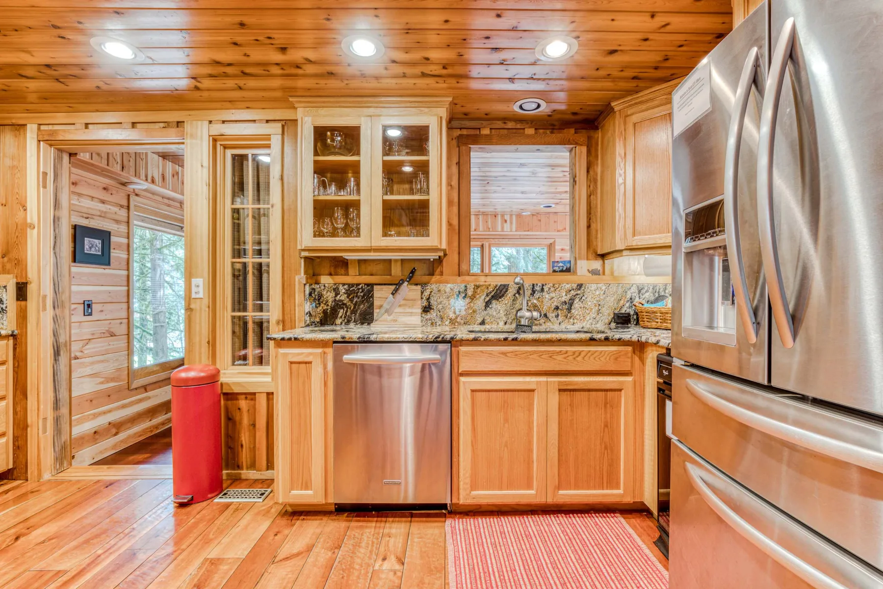 Una cocina revestida de madera con fregadero central, electrodomésticos de acero inoxidable y un salpicadero estampado.