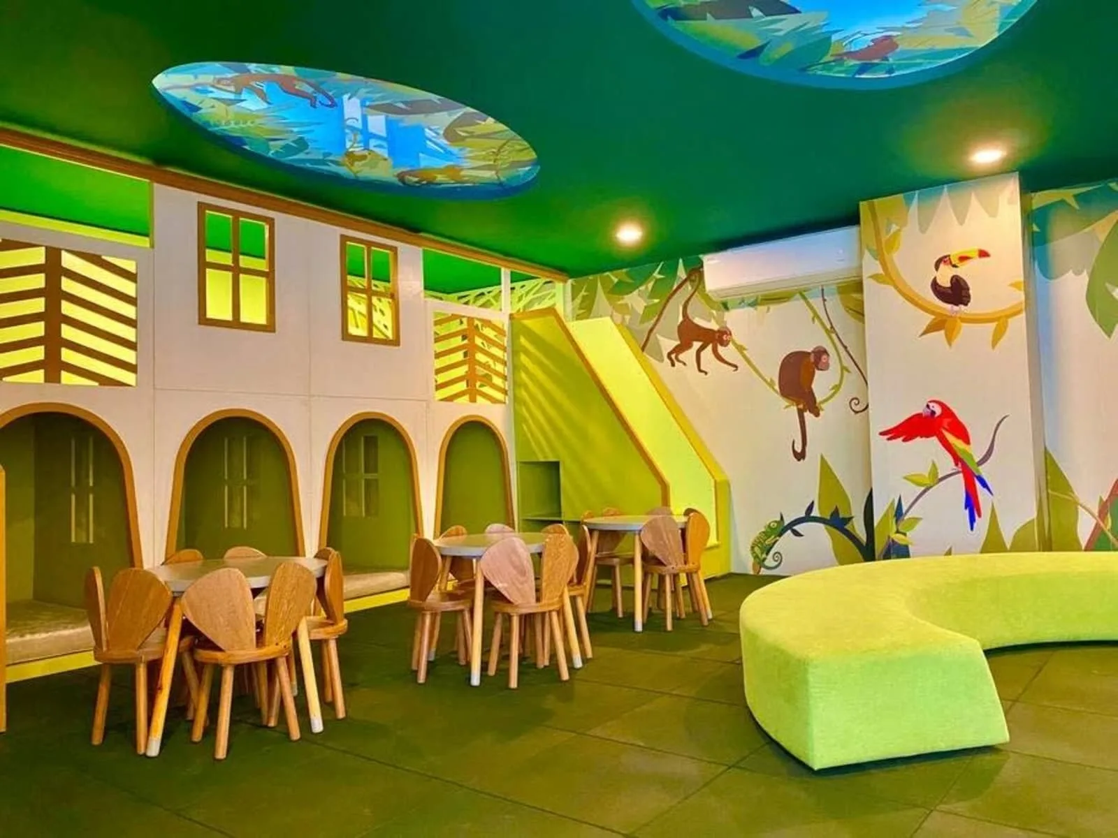Zona común: Un área de juegos interior colorida con mesas infantiles y murales de animales.