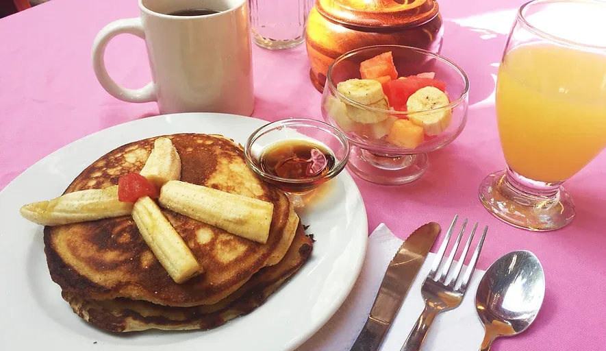 Representative hotel space: A breakfast setting with pancakes, fruit, and drinks on a table.