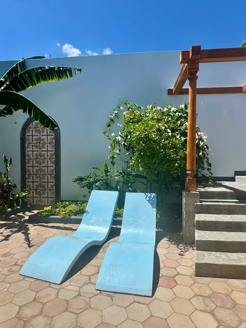 Representative hotel space: A sunny courtyard with two blue reclining loungers beside a stone staircase.